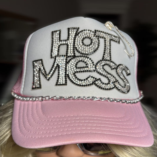Pink cap with 'Hot Mess' text in rhinestones on a blurred background