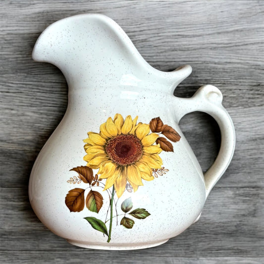 White ceramic pitcher with sunflower design on a wooden surface