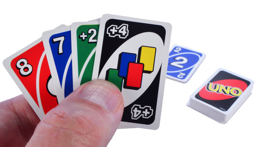 Hand holding a selection of Uno game cards with a clear background